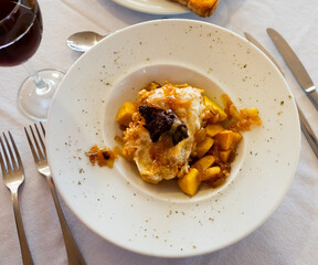 Spanish traditional cuisine, Huevos rotos con morcilla on a white ceramic plate