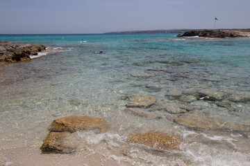 Rocky beach with a turquoise blue sea and waves in spain
