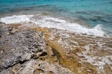 Rocky beach with a turquoise blue sea and waves in spain