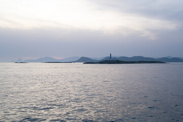Lighthouse on a Mediterranean island during sunset.