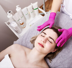 Obraz na płótnie Canvas Beautiful girl with piercing doing facial massage in a beauty salon