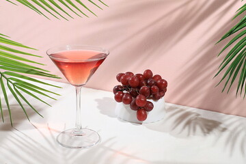 Modern still life with alcoholic margarita cocktail and grapes on pastel background with long hard shadows, minimal concept for bar, cafe, advertising banner, selective focus, space for text
