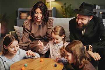 High angle view at modern jewish family playing traditional dreidel game in cozy home setting