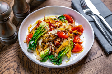dish salad with mussels avocado greens tomatoes almonds in a restaurant