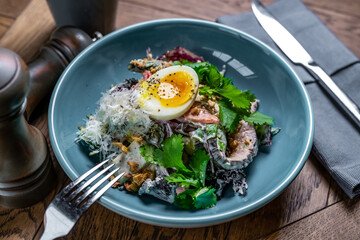 a dish of ham with herbs and an egg in a restaurant