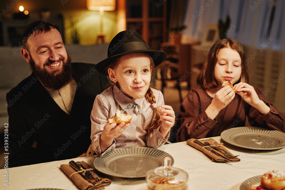 Wall mural portrait of happy jewish father with two daughters at dinner table in cozy home setting