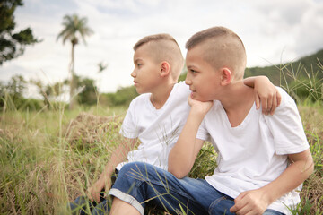 Fototapeta premium two Latino children sitting in the middle of a field resting at sunset