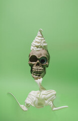 Skull with one eye and ice cream on the head instead of hat. Green background. Halloween setting