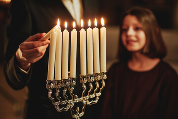 Close up of jewish man lighting silver menorah candle during Hanukkah celebration , copy space