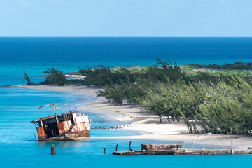 The wreck of an old abandoned ship lies by the shore of Grand Turk in Turks and Caicos on a bright...