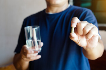 Closeup man hold glass of water and capsule pills to take medicine. Concept : Health care, health...