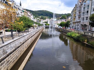 Obraz premium Karlove Vary Chech fountain, river and white road with trees