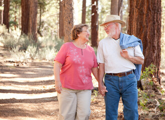 Loving Senior Couple Hold Hands Walking Together In a Forest