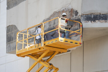 unknown workers repair hurricane damage to a building while on a work lift