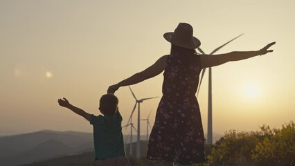 Lifestyle video of a family together near a wind farm in the mountains. The concept of freedom and happiness, mother and son melt hands and fly. Environmentally clean wind energy. 