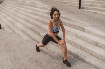 A girl in sportswear doing leg lunges during the workout outside