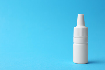 Bottle of medical drops on light blue background. Space for text