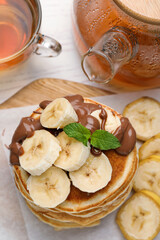 Tasty pancakes with sliced banana served on wooden board, top view