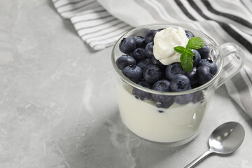 Delicious yogurt with blueberries served on grey marble table, space for text