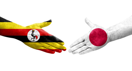 Handshake between Japan and Uganda flags painted on hands, isolated transparent image.