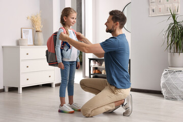 Happy father preparing his daughter to school at home
