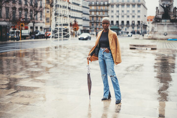 A young svelte black female with short hair painted white is standing on the wet ground of Lisbon...