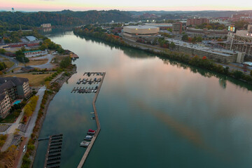 an aerial shot of the silky green waters of the Tennessee River at sunset with a boat dock and autumn colored trees and lush green trees in Knoxville Tennessee USA - obrazy, fototapety, plakaty