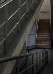 Stairs leading to interior view of public underpass with white tiled walls and CCTV. Space for text, Selective focus.