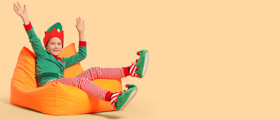 Little boy in costume of elf on beige background with space for text
