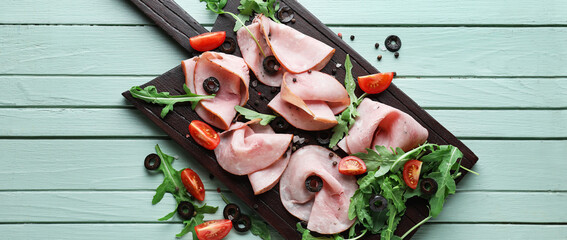 Board with slices of tasty ham, tomatoes, olives and arugula on color wooden background