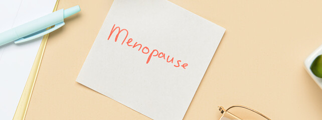 Paper with word MENOPAUSE on beige background
