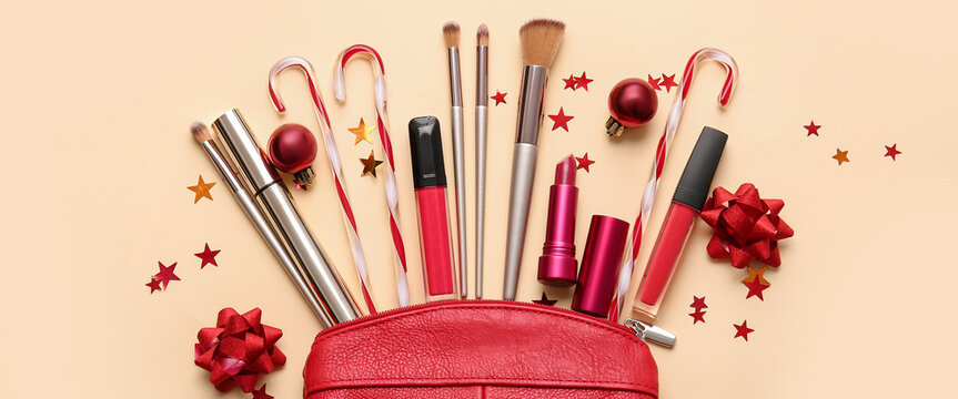 Makeup bag with decorative cosmetics, brushes and Christmas decor on light color background
