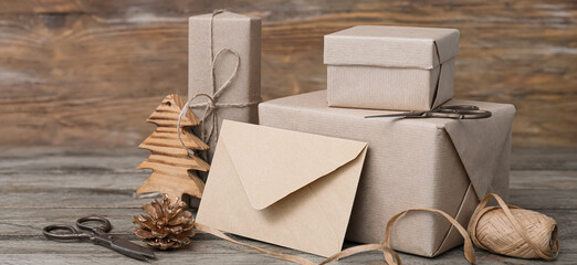 Different gift boxes for Christmas with envelope on wooden background