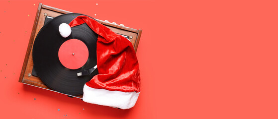 Record player and Santa hat on red background with space for text