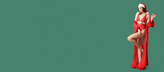 Sexy young woman in Santa hat on green background with space for text