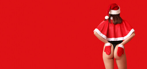 Pretty young woman in sexy Santa costume on red background with space for text - obrazy, fototapety, plakaty