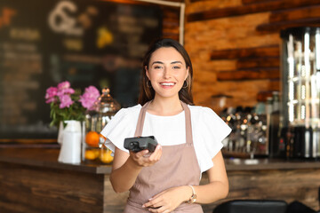 Beautiful business owner with payment terminal in her cafe