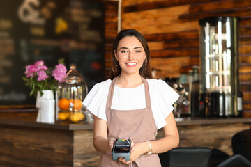 Beautiful business owner with payment terminal in her cafe
