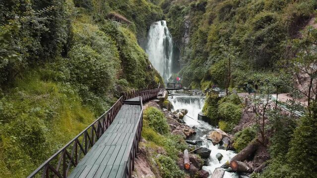 Aerial View Along Empty Wooden Bridge Leading To Peguche Waterfalls In Otavalo. Dolly Back