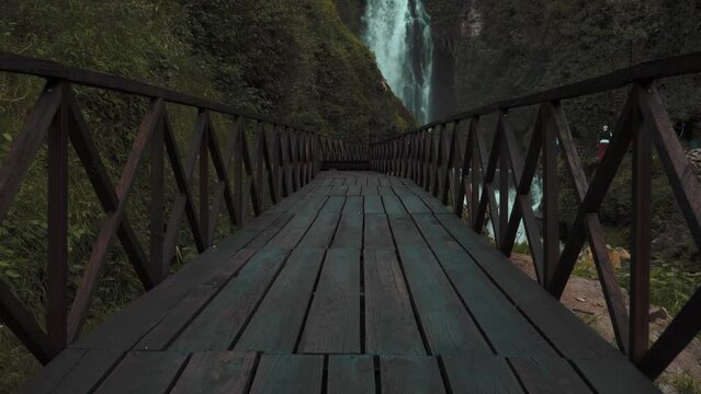 Low Angle View Along Empty Wooden Bridge Leading To Peguche Waterfalls In Otavalo. Slow Pan Up