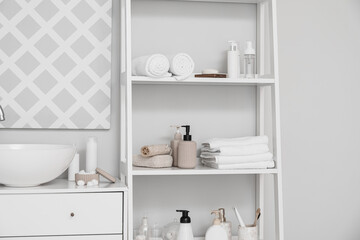 Fototapeta na wymiar Modern sink and shelf unit with bath accessories near white wall