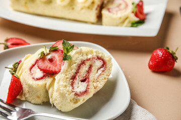 Plate with slices of tasty strawberry roll cake on table, closeup