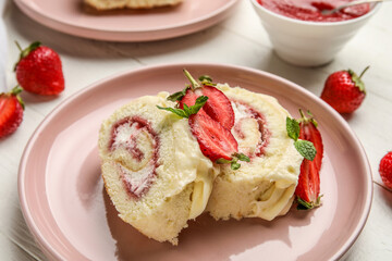 Plate with slices of tasty strawberry roll cake on light wooden table, closeup