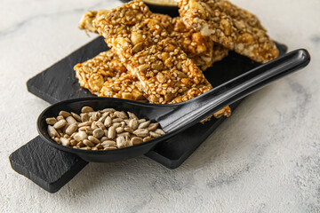 Spoon of sunflower seeds and sesame kozinaki on light background, closeup