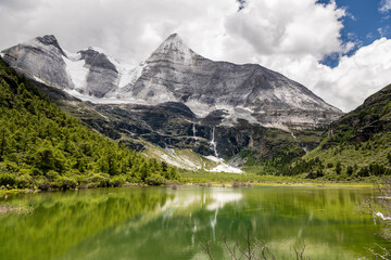 Nature scene of the Pearl Lake with Chenrezig (Xiannairi) Holy Snow Mountain background at Yading winter season. It is beautiful green lake at Yading national parks , Daocheng, China