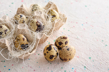 Obraz premium Cardboard holder with fresh quail eggs on light background, closeup