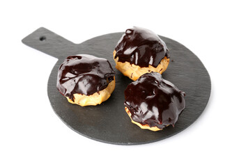 Slate board with delicious eclairs on white background, closeup