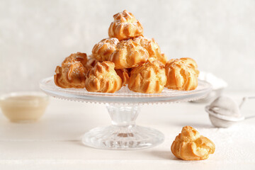 Dessert stand with delicious eclairs on light table