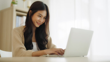 Young asian woman working at home. Female using computer laptop on desk at house