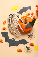 Paper bats with Halloween pumpkin, skeleton hand and candy corns on beige background